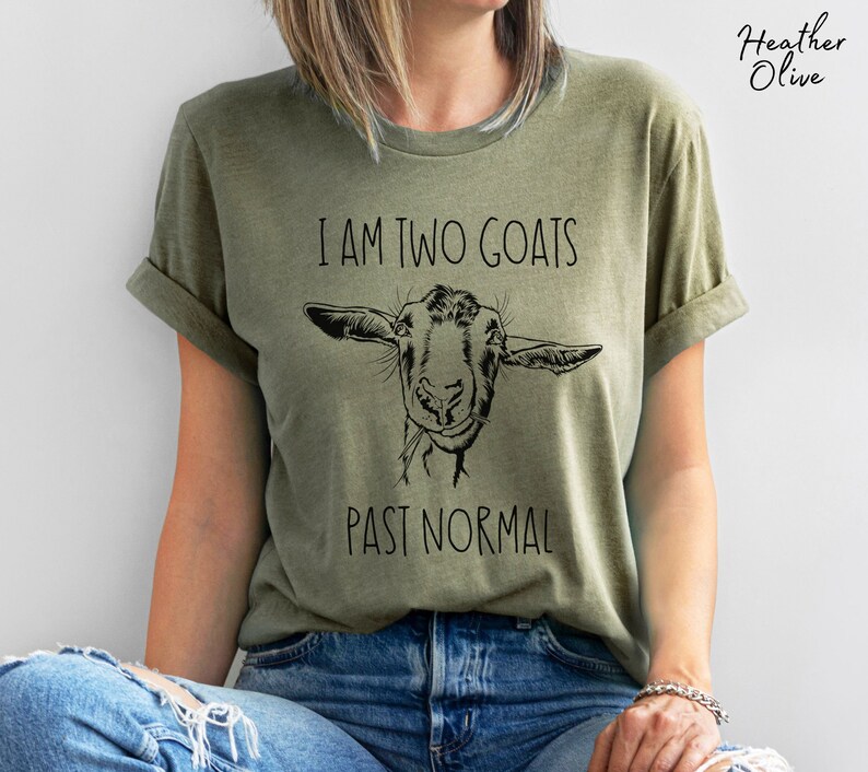 May include: A green t-shirt with the text "I am two goats past normal" and a black and white illustration of a goat's head.