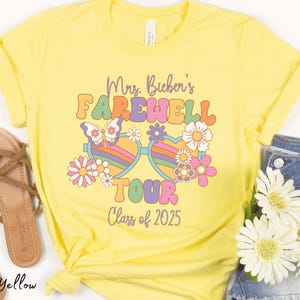 May include: Yellow t-shirt with a retro-style graphic that says "Mrs. Bichen's Farewell Tour Class of 2025". The graphic features a pair of rainbow heart-shaped sunglasses with a butterfly and flowers.