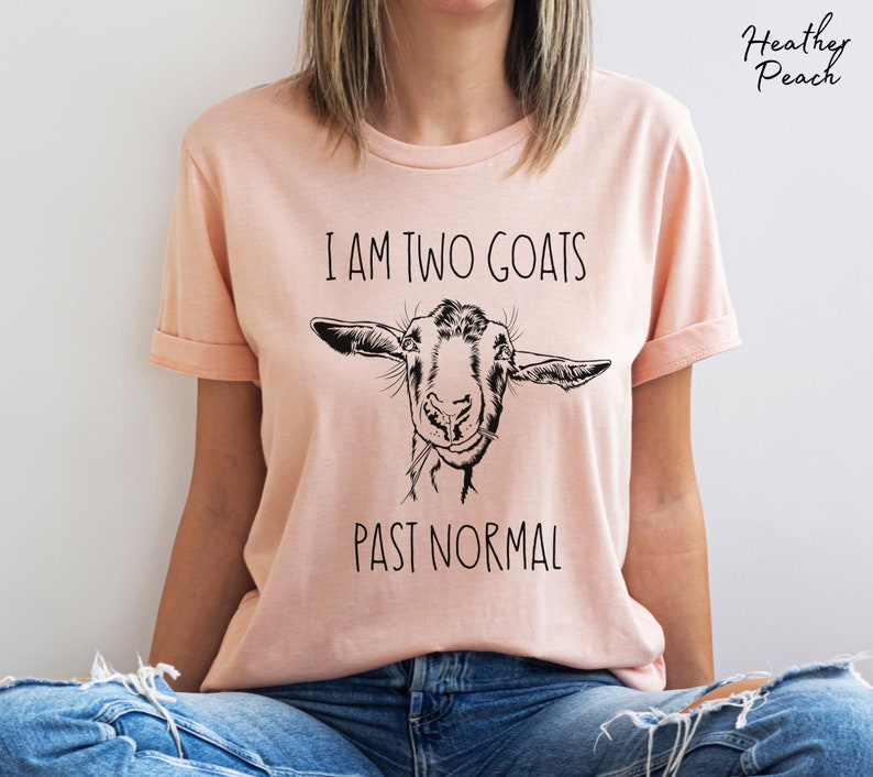 May include: A pink t-shirt with a black and white goat illustration and the text "I am two goats past normal".