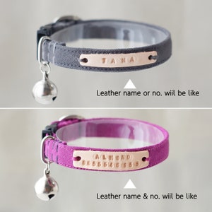 May include: Two cat collars with a bell charm. The first collar is gray with a leather name tag that says "TAMA". The second collar is purple with a leather name tag that says "ALMOND 0655546955".