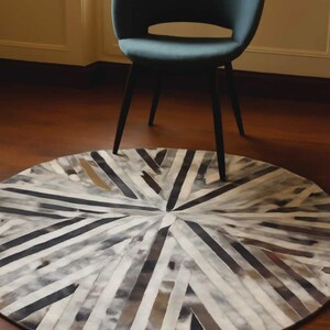 May include: A round rug with a geometric pattern of alternating black, white, and brown stripes. A teal chair with black legs is positioned above the rug. The rug's design radiates from the center.