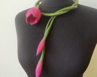 May include: A pink felt flower necklace with green felt stems. The necklace is displayed on a black mannequin.