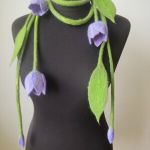 Make a bold, artistic statement with this handmade felted necklace featuring delicate lilac tulip flowers and soft green woolen leaves.