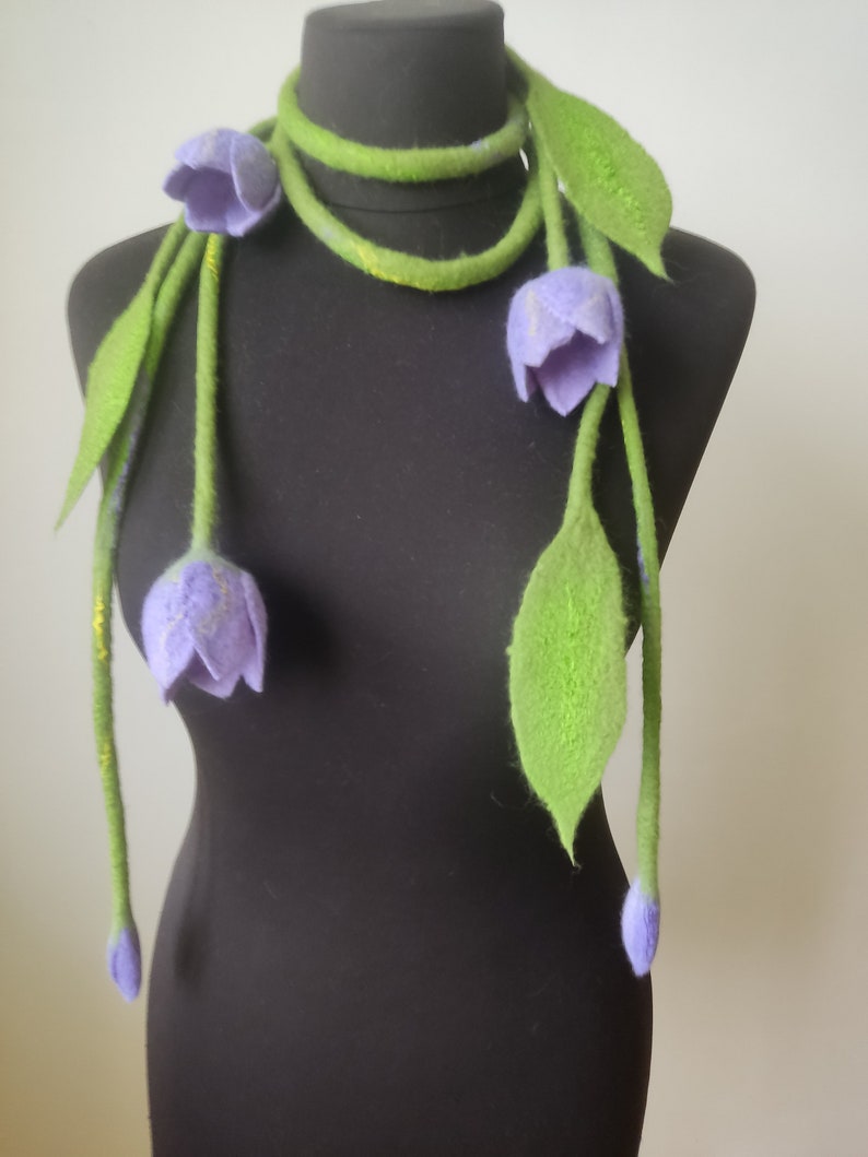 Make a bold, artistic statement with this handmade felted necklace featuring delicate lilac tulip flowers and soft green woolen leaves.