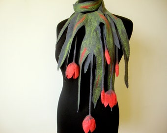 May include: A felted wool scarf in shades of gray, green, and red, displayed on a black mannequin. The scarf features a leaf-like design with red accents and dangling red flower-shaped elements, creating a unique, artistic accessory.