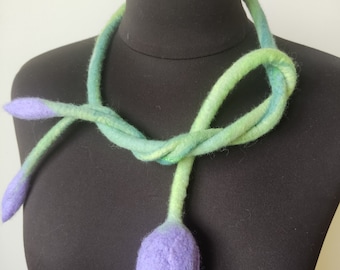 Puede incluir: Un collar de lana de fieltro verde y azul con un colgante de flor de fieltro morado.