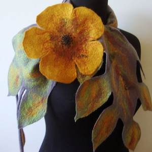 May include: A felted wool scarf with a large yellow flower and green leaves. The scarf is made of a soft, textured fabric and has a unique, handmade look.