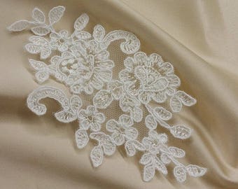 May include: White lace applique with a floral design on a beige fabric background.