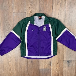 May include: A vintage Nike windbreaker jacket in green, purple, and white. The jacket features a full zipper, a small Nike logo, and a team logo on the chest. The sleeves are purple with white accents.