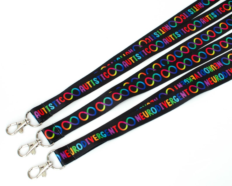 May include: Four black lanyards with rainbow infinity symbols and the words "AUTISTIC" and "NEURODIVERGENT" printed on them. Each lanyard has a silver clip.