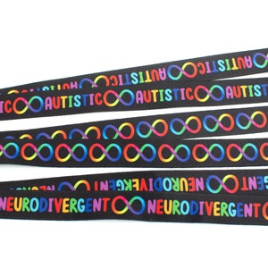 May include: Five black ribbon lanyards with rainbow infinity symbols and the text "AUTISTIC" and "NEURODIVERGENT" printed on them.