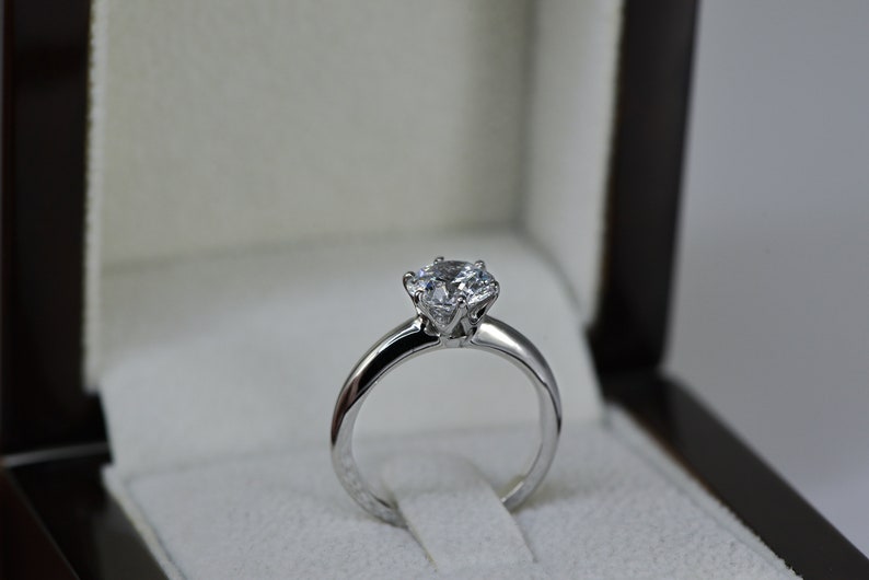 May include: A silver engagement ring with a large, round, clear diamond in a classic setting.