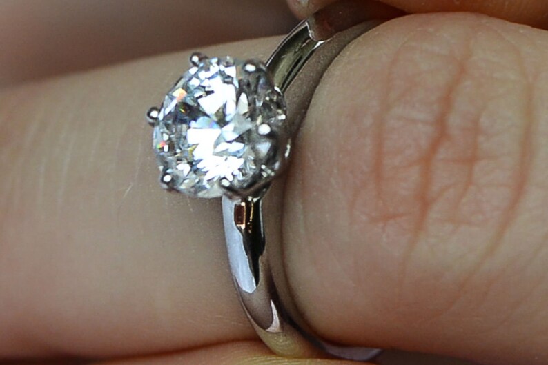 May include: A silver engagement ring with a large, round, clear diamond.