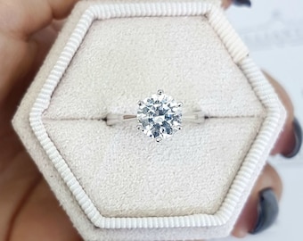 May include: A white gold engagement ring with a large, round, brilliant cut diamond in a six-prong setting.