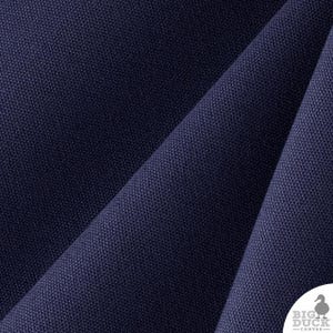 Op de afbeelding: Een diep marineblauwe canvasstof met een zichtbare geweven textuur en diagonale plooien. In de rechterbenedenhoek staat een wit cirkelvormig logo met een silhouet van een eend en de tekst BIG DUCK CANVAS in een strak, schreefloos lettertype.
