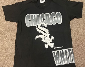 May include: Black t-shirt with a white graphic of the Chicago White Sox logo and the word "Chicago" in a gradient font.