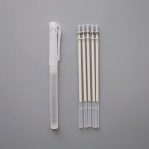 Op de afbeelding: Vijf witte navulbare inktpatronen en een transparante plastic pen met een witte dop.