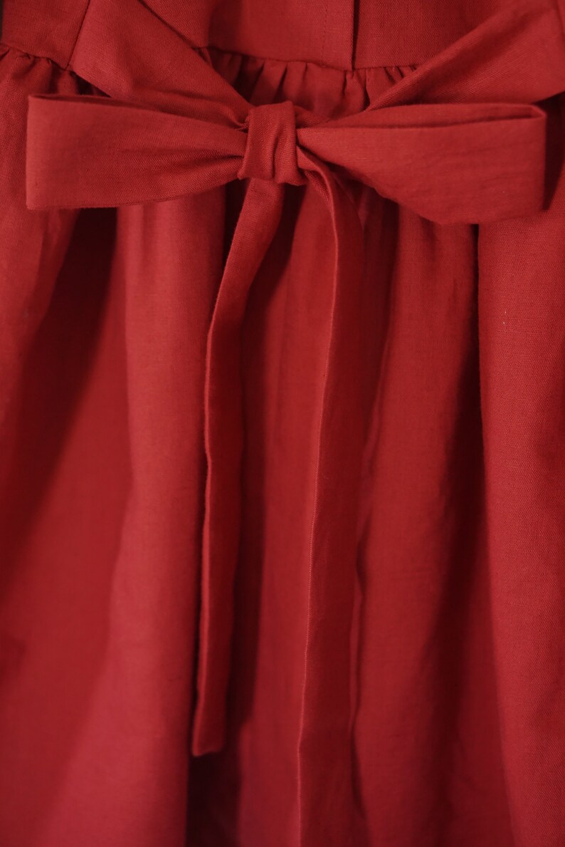 Puede incluir: Un vestido rojo con un gran lazo en la cintura.