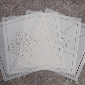May include: Set of five white plastic stencils with different geometric designs. The stencils are square shaped and have a decorative border.