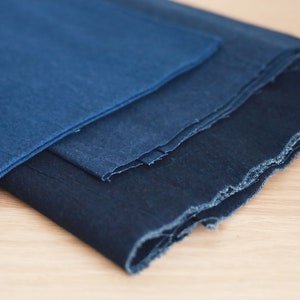 May include: Three pieces of indigo dyed fabric stacked on top of each other. The fabric is a deep blue color and has a rough, textured surface.