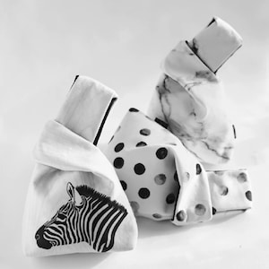 Pu&ograve; includere: Tre borse di tessuto con motivi diversi. Una borsa ha una stampa zebra in bianco e nero, un'altra ha pois neri su sfondo bianco e la terza ha un motivo a marmo bianco.