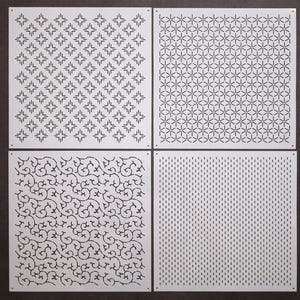 Op de afbeelding: Vier vierkante, witte metalen panelen met verschillende geometrische patronen. De patronen omvatten sterren, in elkaar grijpende zeshoeken, wervelende lijnen en verticale streepjes. De panelen zijn gerangschikt in een 2x2 raster tegen een donkere achtergrond.