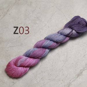 May include: A skein of yarn in shades of pink and purple. The yarn is twisted and has a gradient colour effect. The yarn is labelled "Z03".