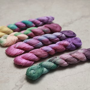 May include: Six skeins of yarn in various shades of pink, purple, green, and yellow. The yarn is twisted and has a soft, fuzzy texture. visible creative mending sashiko thread quilting thread