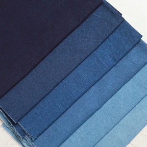 May include: A stack of denim fabric swatches in various shades of blue, ranging from dark indigo to light blue.