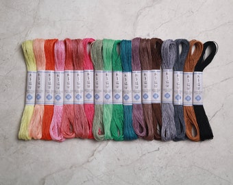 May include: A set of 14 spools of embroidery floss in various colours, including yellow, orange, pink, red, green, blue, brown, grey, and black. Each spool has a label with Japanese text.