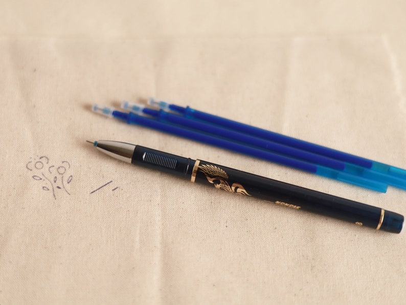 May include: A blue and gold pen with a decorative design on the barrel. Four blue ink refills are also pictured.