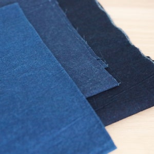 May include: Three pieces of indigo dyed fabric in different shades of blue, from light to dark.