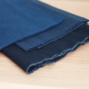 May include: Three pieces of indigo blue fabric folded on top of each other. The fabric has a rough, textured surface.