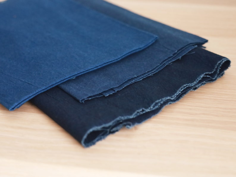 May include: Three pieces of indigo blue fabric folded on top of each other. The fabric has a rough, textured surface.