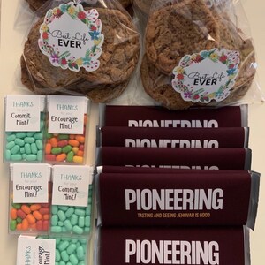 May include: An assortment of treats, including large cookies in clear bags with floral "Best Life Ever" stickers, mints in clear boxes with "Thanks for your Commit Mint!" and "Encourage Mint!" labels, and maroon chocolate bars labeled "PIONEERING".