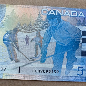 Eishockey Notiz. Kanada 5 Dollar Geldschein. Kanadische Währung. Wintersport, Kinder Eislaufen, Rodeln, Papiergeld und Hockey spielen.