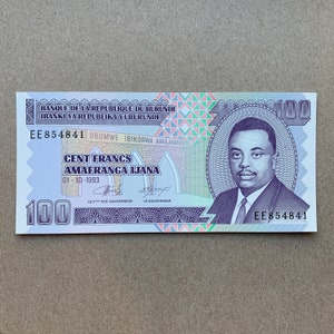 1990er Jahre Burundi 100 Franc Banknote. Burundische Währung. Torbogen, Prinz Rwagasore. Papiergeld Erinnerungsstücke. Haus Bau Szene.