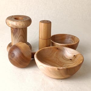 May include: A selection of handcrafted wooden items, including two small bowls, a spool-shaped object, and a cylindrical container. The items are made of light-coloured wood with visible grain patterns and a natural finish.