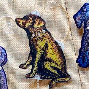 May include: A brown and gold dog ornament with a rhinestone collar. The ornament is sitting on a white background and has a gold wire hanger.