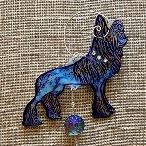 May include: A decorative ornament in the shape of a wolf, featuring shades of blue and black with a textured pattern. The wolf has a silver wire loop for hanging, and a dangling iridescent crystal bead. Three small crystals are embedded on the wolf's back.