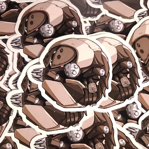 May include: A die-cut sticker featuring a stylized illustration of a mechanical creature with a segmented, rounded shell in shades of cream and dark brown. The creature has sharp, claw-like appendages, small circular details, and glowing red eyes.