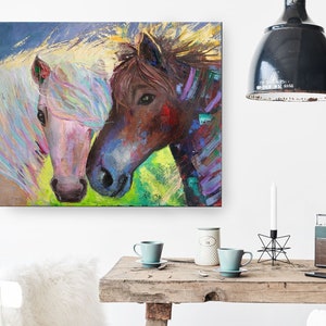 May include: A painting of two horses, one white with a pink nose and the other brown with a colorful mane, looking at each other.
