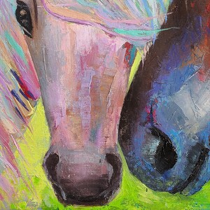 May include: A close-up of two horses' faces, one with a pink and purple mane and the other with a blue and black mane. The horses' noses are touching, and the background is a green field.