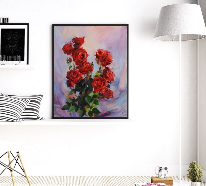 May include: A framed painting of a bouquet of red roses with green leaves. The artwork features a vibrant display of flowers against a soft, blended background of pink, blue, and purple hues. The painting is in a black frame.