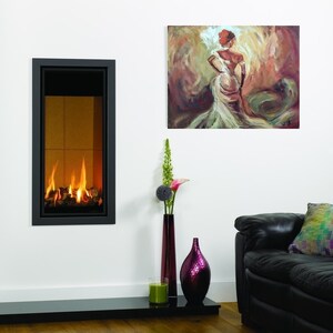K&ouml;nnte beinhalten: Ein moderner Kamin mit schwarzem Rahmen und einer Glasfront, in dem ein Feuer brennt. Der Kamin ist an einer wei&szlig;en Wand montiert, &uuml;ber ihm h&auml;ngt ein Gem&auml;lde einer Frau in einem wei&szlig;en Kleid. Im Vordergrund befindet sich ein schwarzes Ledersofa mit einem bunten Kissen.