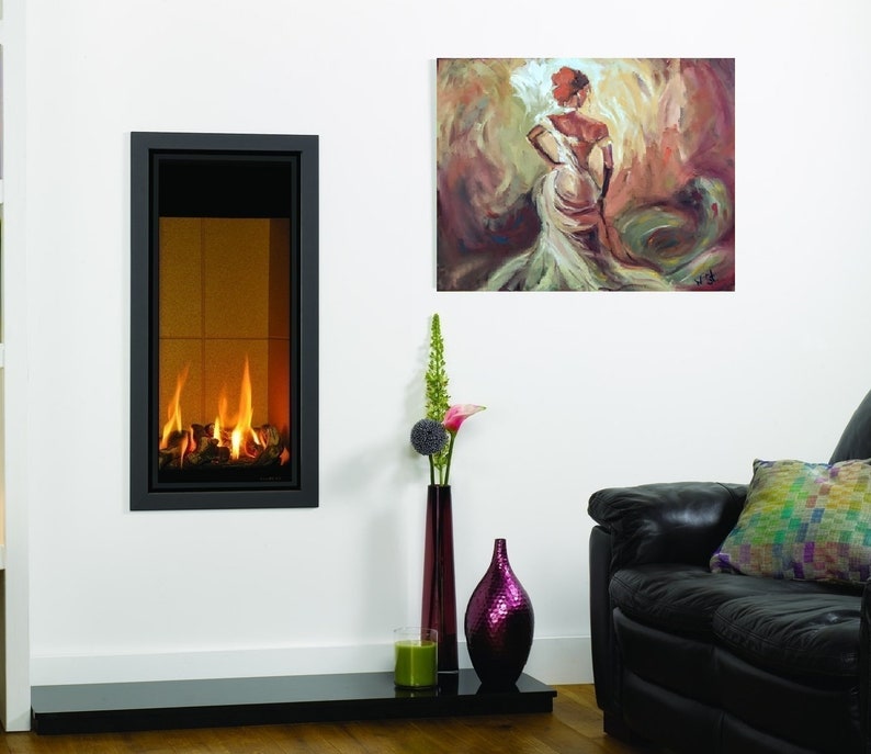 K&ouml;nnte beinhalten: Ein moderner Kamin mit schwarzem Rahmen und einer Glasfront, in dem ein Feuer brennt. Der Kamin ist an einer wei&szlig;en Wand montiert, &uuml;ber ihm h&auml;ngt ein Gem&auml;lde einer Frau in einem wei&szlig;en Kleid. Im Vordergrund befindet sich ein schwarzes Ledersofa mit einem bunten Kissen.