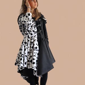 Peut inclure: Un manteau noir et blanc unique, avec un motif de taches de dalmatien d'un côté et noir uni de l'autre. Le manteau a une capuche et des fermetures à bascule, porté avec un legging noir.