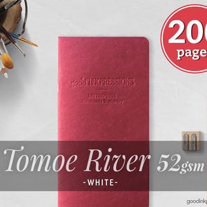 Op de afbeelding: Een rode Tomoe River notitieboek met 200 pagina's, 52 gsm, en de tekst "goodINKpressions". Een potlood en een puntenslijper liggen naast het notitieboek. Het notitieboek is handgemaakte briefpapier.