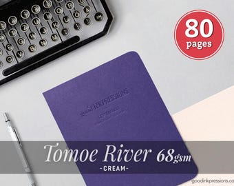 May include: A purple notebook with the embossed text good INKPRESSIONS LETTERPRESS handmade stationery. The cover features Tomoe River 68gsm cream paper. A red circle graphic displays 80 pages. A typewriter and a silver mechanical pencil are visible.