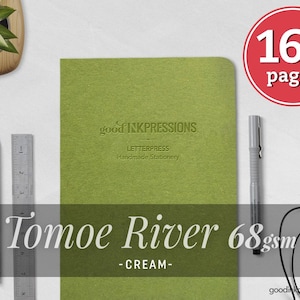 Puede incluir: Un cuaderno verde Tomoe River con el texto "good inkpressions LETTERPRESS Handmade Stationery". El cuaderno tiene 160 páginas y está acompañado de un lápiz, una regla y un bolígrafo. El cuaderno es de color crema.